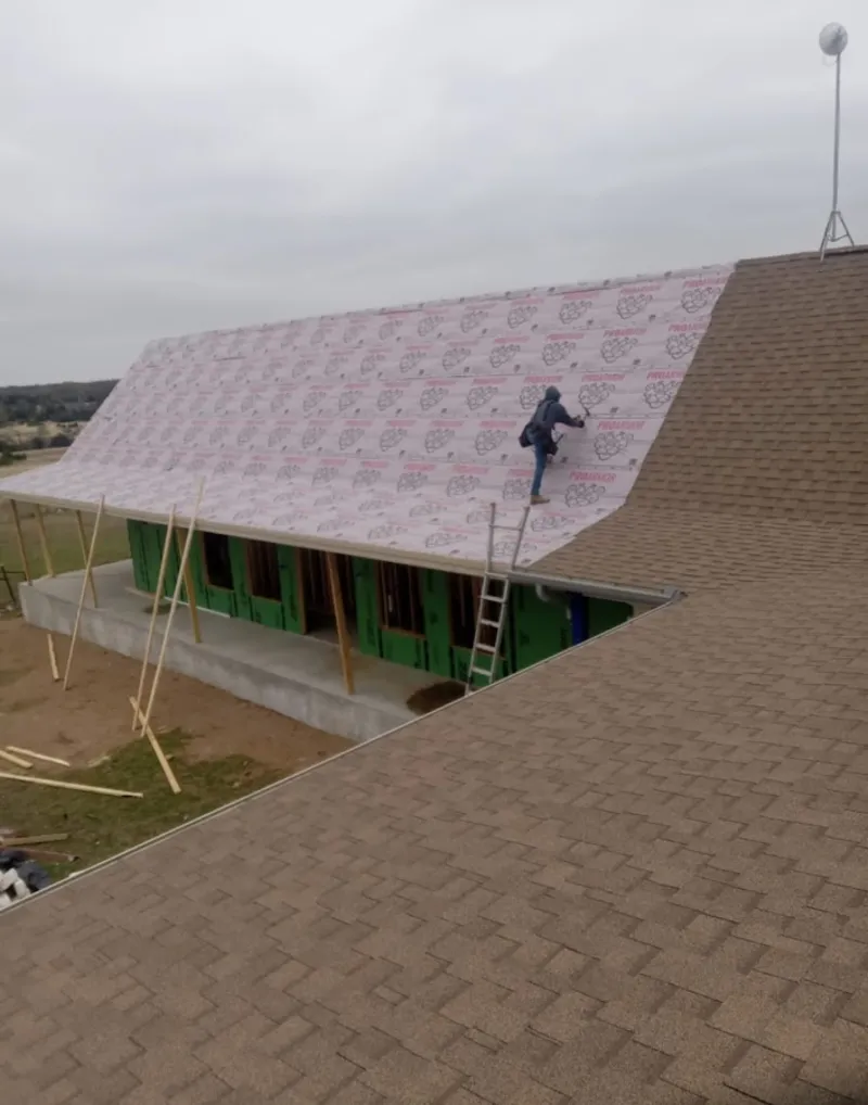 Worker preparing underlayment for a metal roof installation in Hibbing